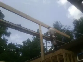 Carpenter setting a ridge beam over a new addition frame — Ice Dam Removal by Roofing Brothers in Krum