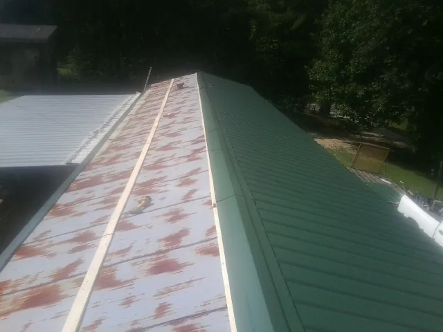 Old rusted panels beside newly installed green metal roofing — Wind Damage Roof Repair by Roofing Brothers in Krum