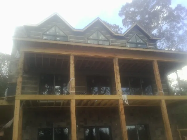 Dormers and porch framing on a large log home under construction — Roof Coating work by our crew in Krum