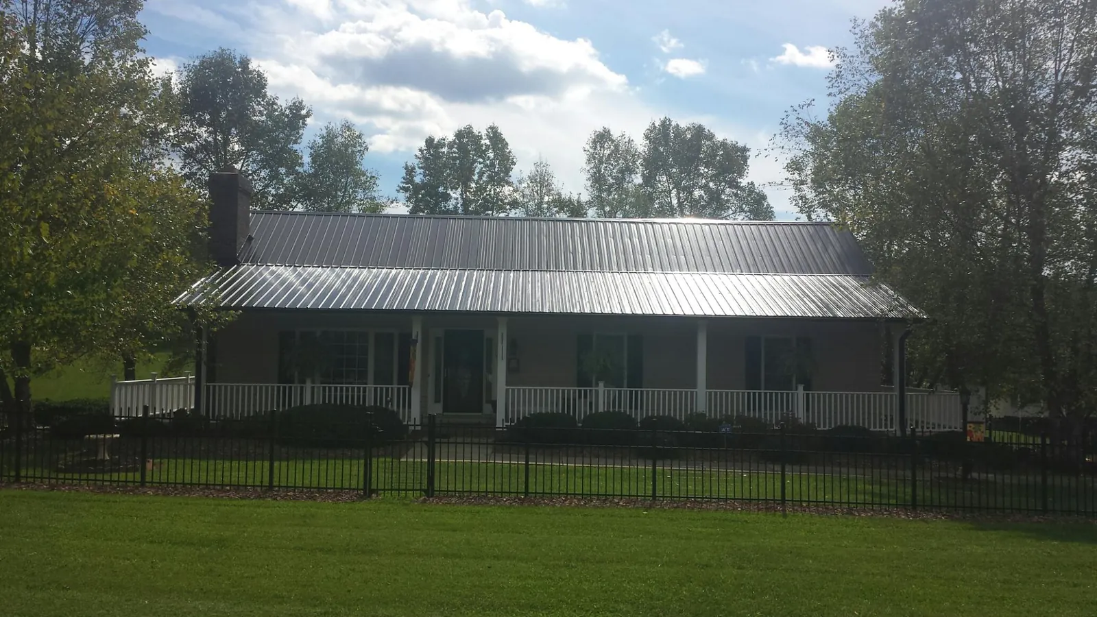 Gray metal roof on a brick ranch with a full width front porch — Gutter Guard Installation work by our crew in Krum