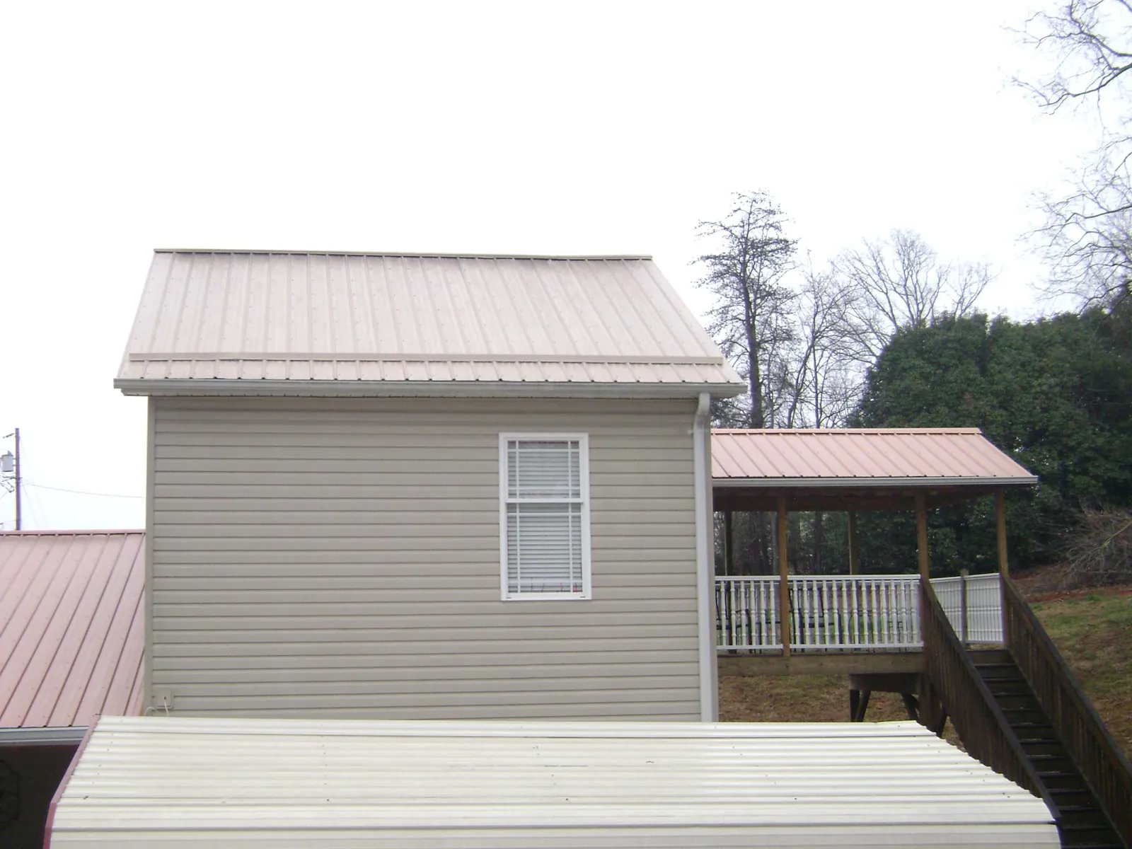 Tan metal roofs on a two story addition and attached porch in Krum