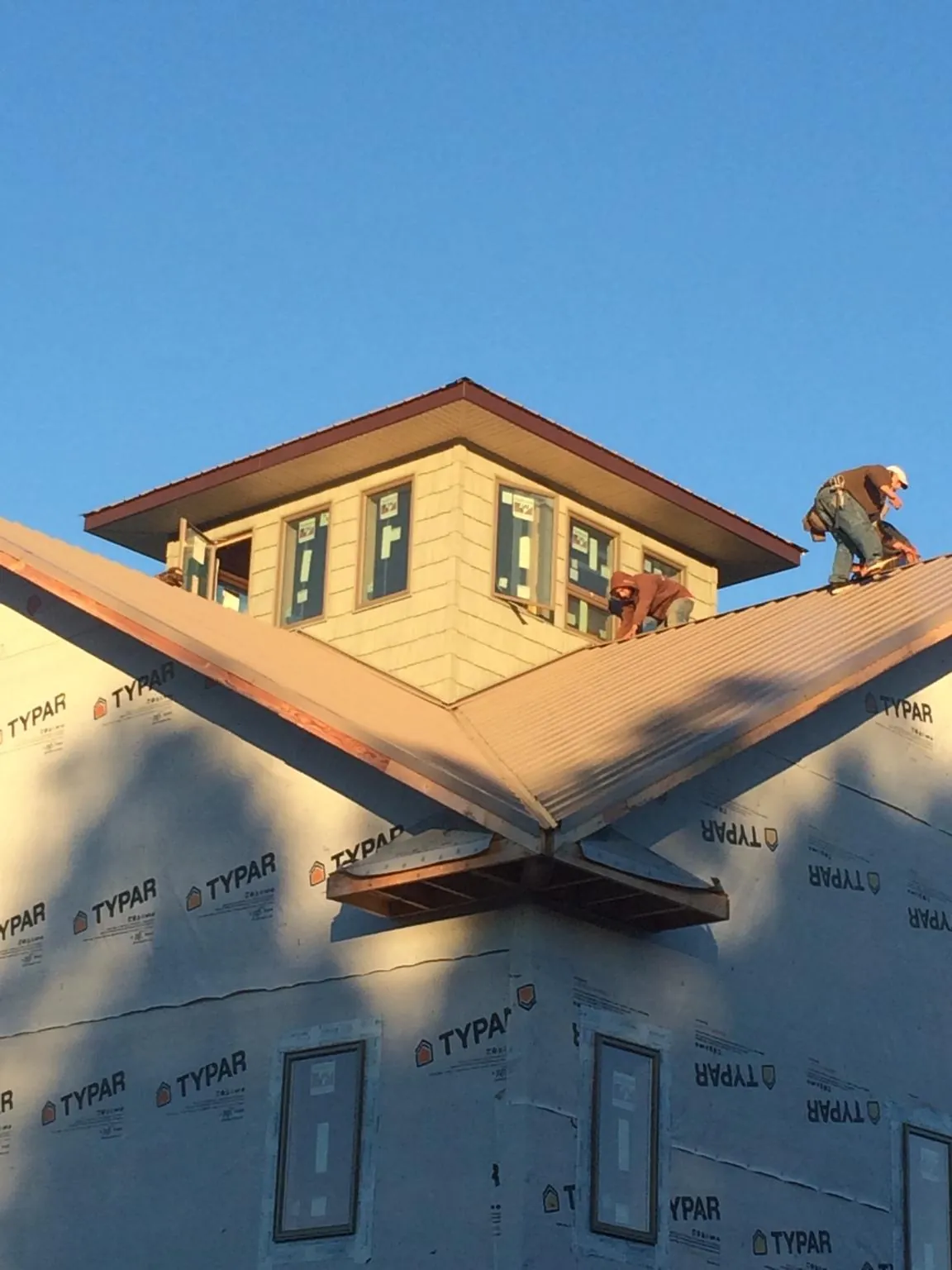 Roofers working around a rooftop cupola on a new metal roof at sunset — Roof Waterproofing in Krum by Roofing Brothers